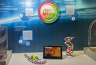 Bild zeigt: Modelle verschiedener Biomoleküle und Tablet-PC vor einer bunten Wand