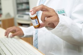 Bild zeigt: Close-up eines Pharmazeuten, der ein Medikament hält